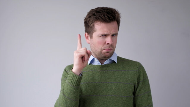 The serious European young man shows a finger up and gives advice or recommendation.