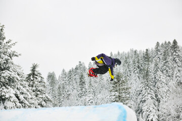 young boys jumping in air ind showing trick with snowboard at winter season