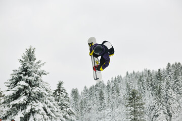 young boys jumping in air ind showing trick with snowboard at winter season