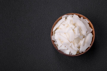 White dry coconut flakes in a wooden bowl prepared for making desserts
