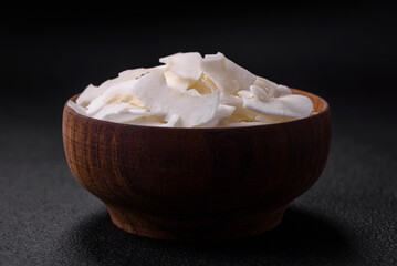 White dry coconut flakes in a wooden bowl prepared for making desserts