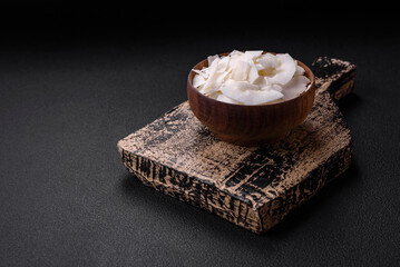White dry coconut flakes in a wooden bowl prepared for making desserts