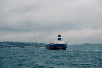 Fototapeta premium An impressive stock photo showcases a cargo ship navigating through Istanbul's Bosphorus Strait on a cloudy day, capturing the essence of maritime charm and the city's iconic skyline.