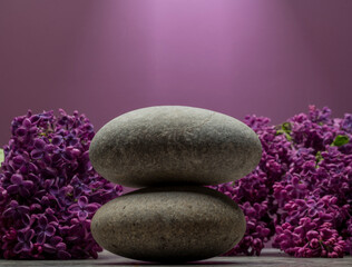 Obraz na płótnie Canvas gray zen stone and purple lilac branch with flowers for product stand background podium on lilac background