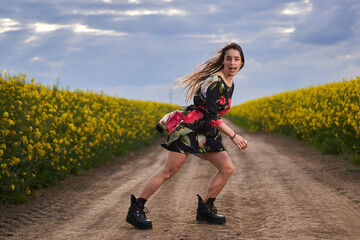 Fototapeta premium Beautiful latino woman in floral dress in a canola field