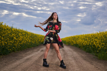 Obraz premium Beautiful latino woman in floral dress in a canola field