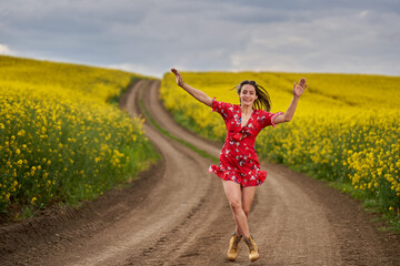 Beautiful latino woman in floral dress in a canola field