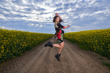 Fototapeta premium Beautiful latino woman in floral dress in a canola field