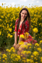 Beautiful latino woman in floral dress in a canola field