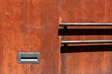 Wood hand railing fixed on the rusty metal wall.
