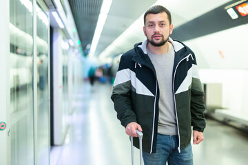 Portrait of young confident male passenger in casual clothing on underground platform