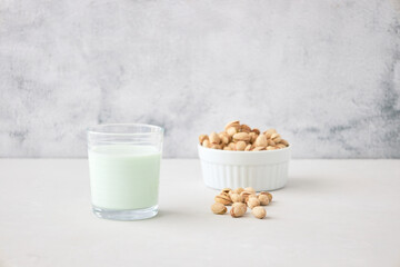 A glass of vegetable milk from nuts on the table next to pistachios. The perfect drink for vegans