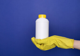 Human Hand In Yellow Glove Holds White Bottle With Pipe Cleaner Granules. Removal Of Blockage In...