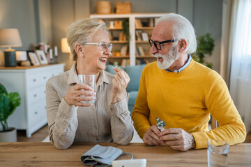 senior couple at home woman take medicine while her husband sit beside