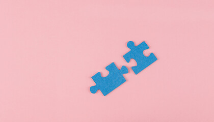 two blue colored jigsaw puzzle pieces coming together on a pink colored background, concept of union, teamwork, compliment, whole
