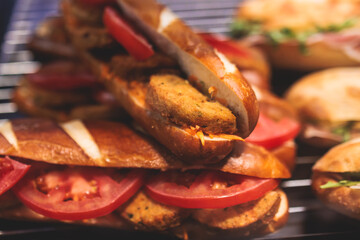 Beautifully decorated catering banquet table with different food snacks and appetizers setting with sandwiches, bagels, baguette club submarine sandwich, on wooden plate, on a party or celebration