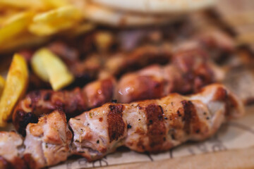 View of Souvlaki on a plate - traditional greek cuisine dish with grilled bbq chicken with french fries and tzatziki sauce served in a taverna cafe restaurant in the streets of Athens, Attica, Greece