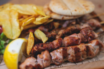 View of Souvlaki on a plate - traditional greek cuisine dish with grilled bbq chicken with french fries and tzatziki sauce served in a taverna cafe restaurant in the streets of Athens, Attica, Greece