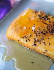 Fried feta cheese wrapped in phyllo pastry with honey and sesame, traditional greek starter snack on a plate served in traditional taverna cafe restaurant in the streets of Athens, Attica, Greece