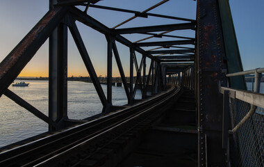 In silhouette back-lit in sunrise structural pattern of truss bridge and leading lines on Tauranga Railway bridge