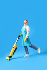 Young woman with vacuum cleaner on blue background