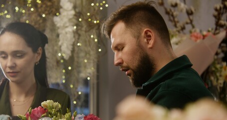 Close up shot of florist entrepreneur add fresh flowers to bunch and look on it in floral shop....