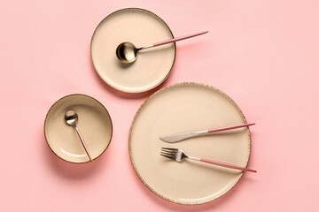 Table setting with clean plates and cutlery on pink background