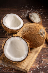 Whole coconut, pieces of coconut and shredded coconut on the table.