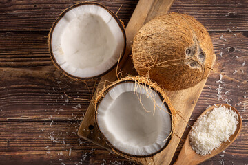 Whole coconut, pieces of coconut and shredded coconut on the table.