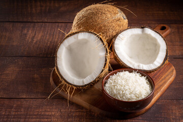 Whole coconut, pieces of coconut and shredded coconut on the table.