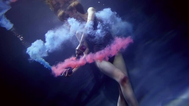 underwater fantasy, beautiful woman in swimsuit floating in depth and coloring water in red and blue