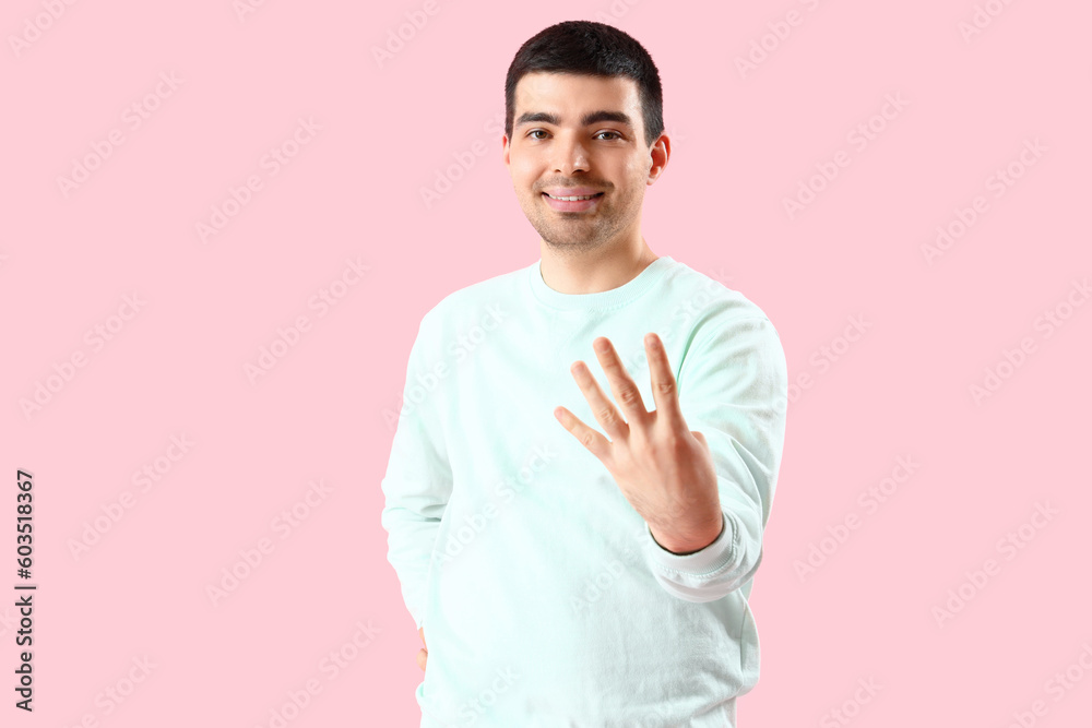 Canvas Prints Young man showing four fingers on pink background