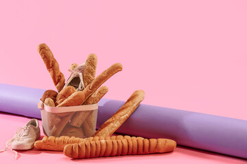 Sportive male sneakers with basket of bread on pink background