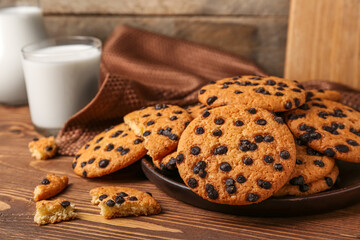 Plate of tasty cookies with chocolate chips on wooden background, closeup