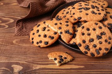 Plate of tasty cookies with chocolate chips on wooden background, closeup