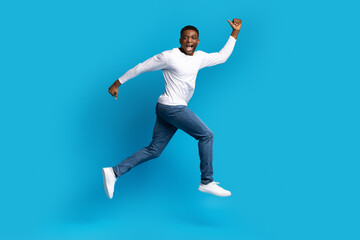 Fototapeta premium Excited african american man running over blue background