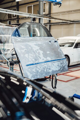 The car body after the accident is covered with putty, primer before painting. The process of disassembled and prepared for painting in the paint chamber by spraying. Service station. Restoring after