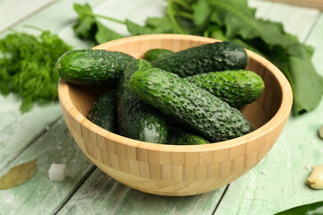 Bowl with fresh cucumbers for preservation on light wooden background