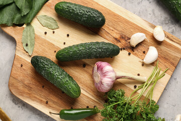 Wooden board with fresh cucumbers and garlic for preservation on table