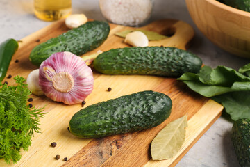 Wooden board with fresh cucumbers and garlic for preservation on table