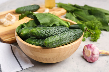 Bowl with fresh cucumbers for preservation on grunge background
