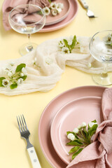Beautiful table setting with blooming tree branches on yellow background