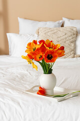 Vase with beautiful tulip flowers on bed, closeup