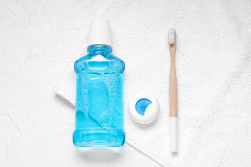 Dental floss, toothbrush and mouthwash on white towel