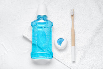 Dental floss, toothbrush and mouthwash on white towel