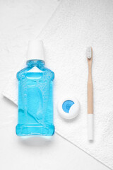 Dental floss, toothbrush and mouthwash on white towel