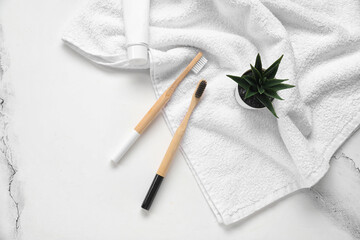 Bamboo toothbrushes with towel on white marble background