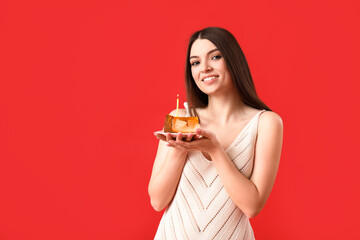 Beautiful young woman with sweet birthday cake on red background