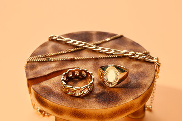 Decorative stand with golden rings and bracelets on orange background