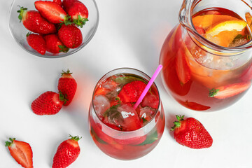 Glass and jug of tasty strawberry juice on white table